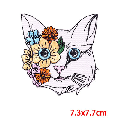 Embroidered patch of a cat's face with flowers on a white background