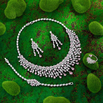 Silver jewelry set with pink stones on a green textured background