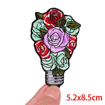 Floral patch held by a finger with dimensions 5.2x8.5cm on a white background