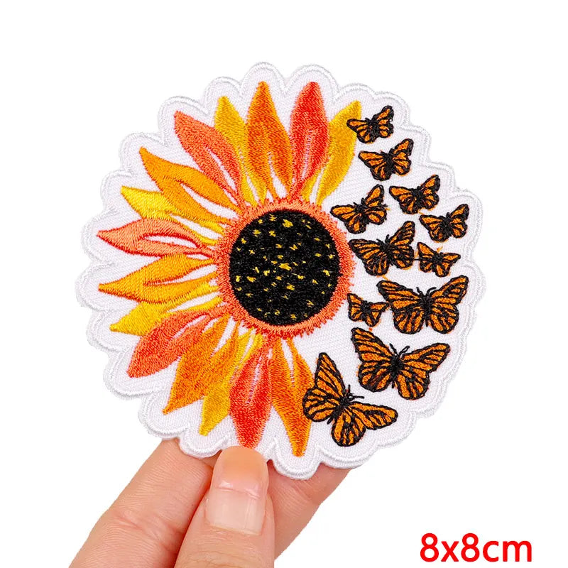 Embroidered patch with sunflower and butterflies held by a hand on a white background
