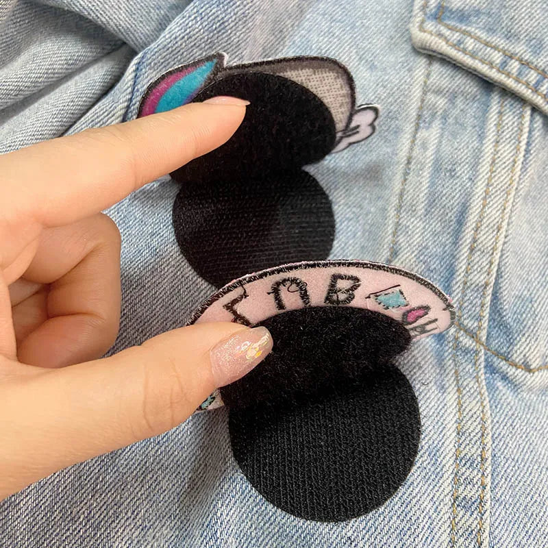 Showing how to apply Black Velcro patches held over a denim jacket with colorful patches.