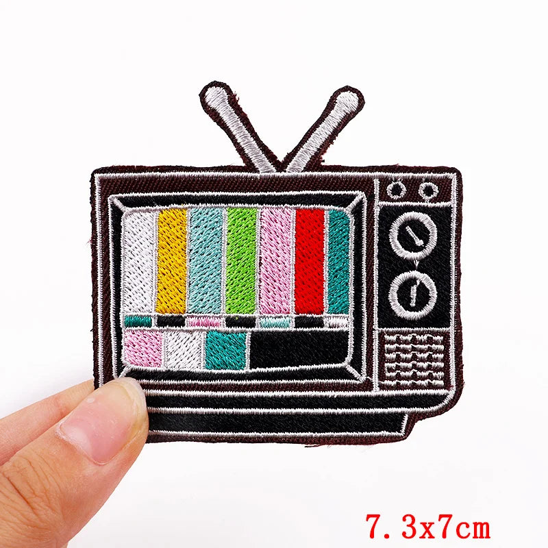 Patch of a vintage television set with test pattern held by a hand, on a white background.