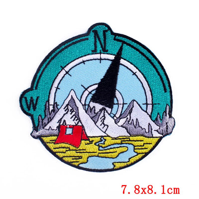 Patch with compass, mountains, and cabin design on a white background