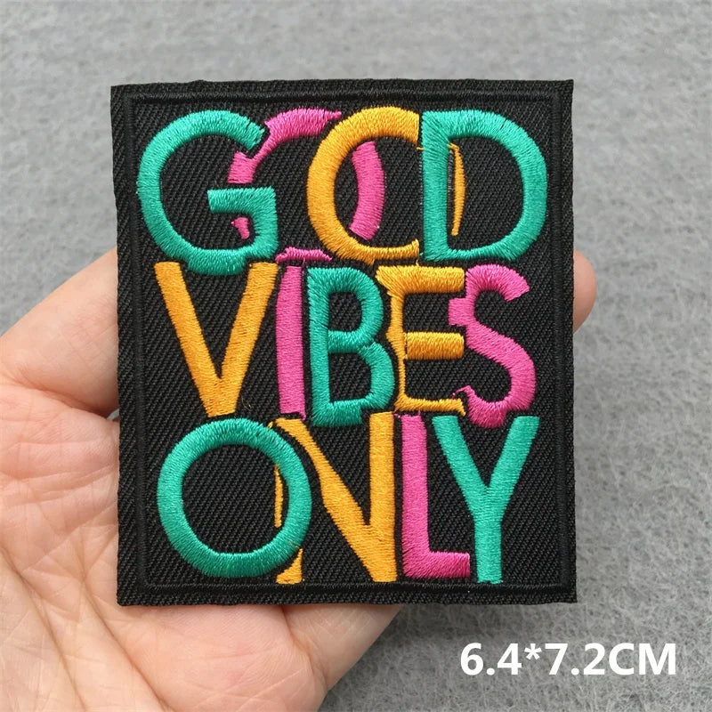 Embroidered patch with 'GOD VIBES ONLY' text held in a hand against a gray background