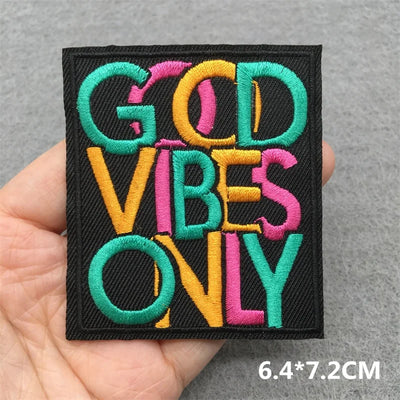 Embroidered patch with 'GOD VIBES ONLY' text held in a hand against a gray background