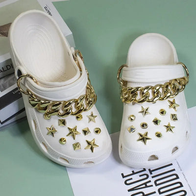 White clogs with gold chains and star embellishments on a light green background.