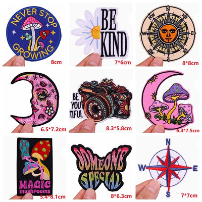 Collection of various patches with different designs and text, held by hands.