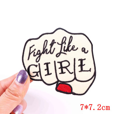 Patch with 'Fight Like a Girl' text held by a hand on a white background