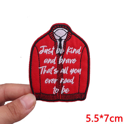 Red jacket patch with text held by a hand on a white background