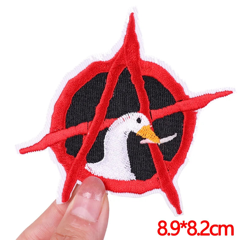 Embroidered patch with a duck design held by a hand, on a white background.