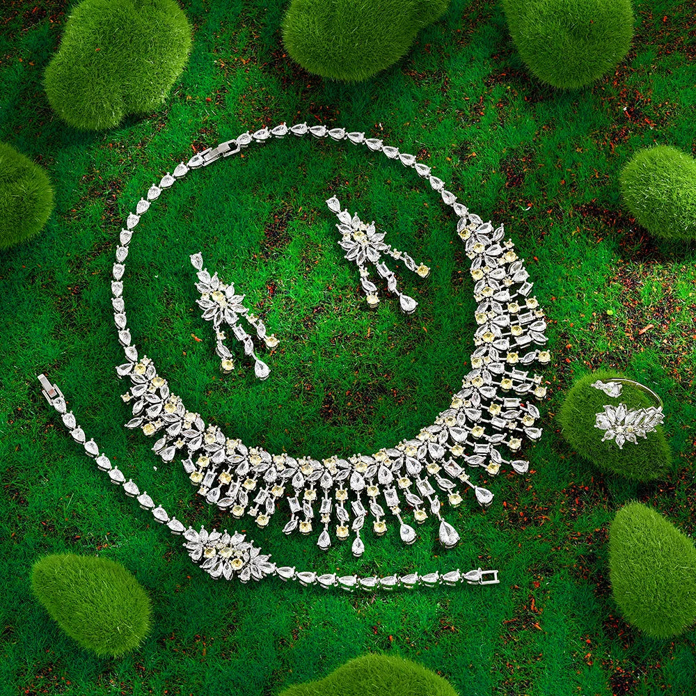 Silver jewelry set including necklace, earrings, ring and bracelet on a green leafy background