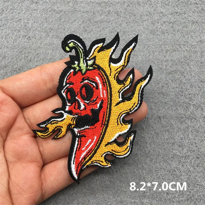 Flaming red pepper patch held in a hand on a gray background