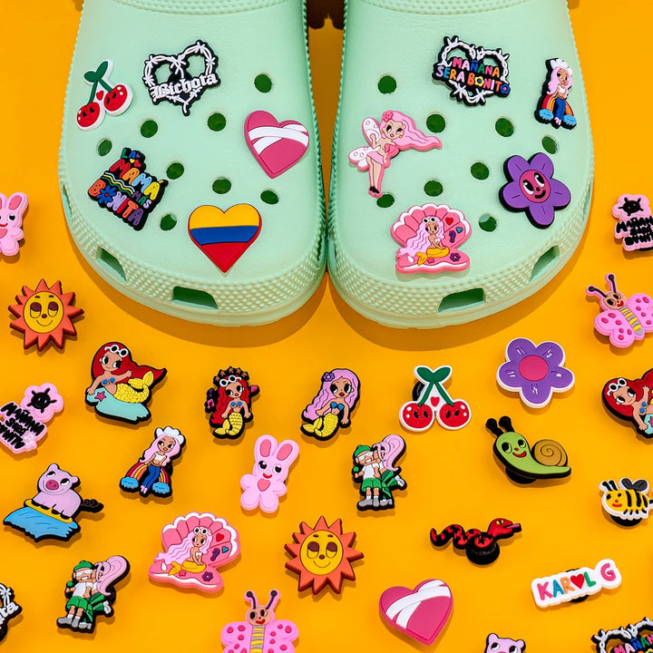 Light green clogs with colorful decorative pins on a yellow background