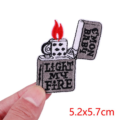 Embroidered patch of a lighter with text held by a hand on a white background
