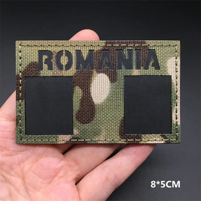 Romania flag Camouflage patch held in a hand against a dark background