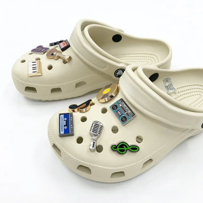 Beige clogs with decorative pins on a white background