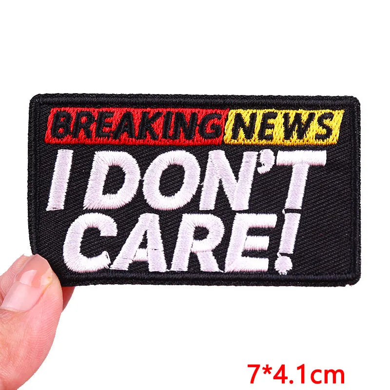 Patch with 'BREAKING NEWS I DON'T CARE!' text held by a hand, with dimensions displayed.