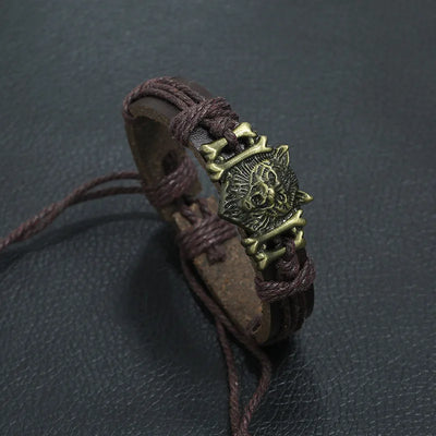 Brown leather bracelet with a bronze lion head emblem on a dark gray background