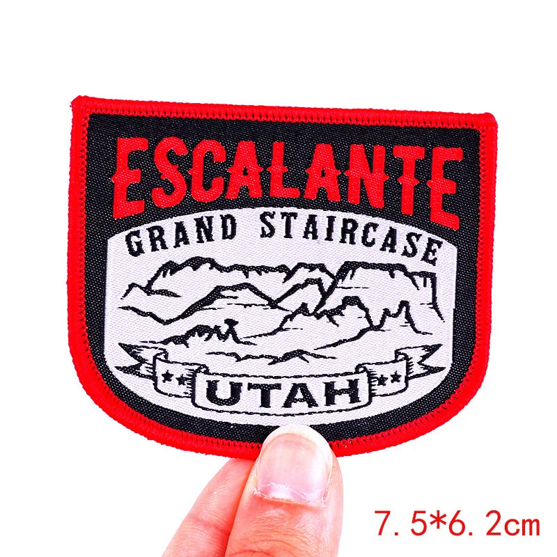 Patch with 'Escalante Grand Staircase Utah' design held by a hand on a white background