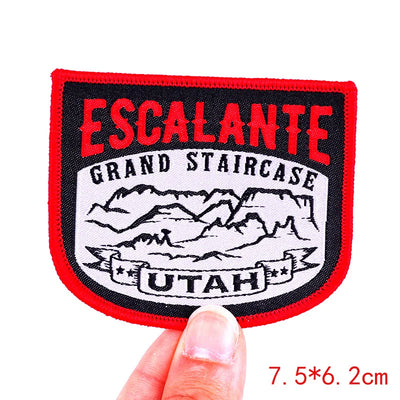 Patch with 'Escalante Grand Staircase Utah' design held by a hand on a white background