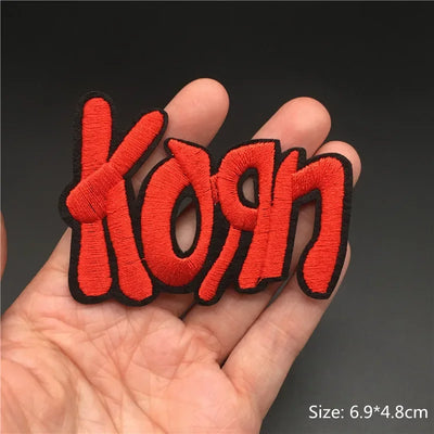 Red 'Korn' patch held in a hand with a dark background