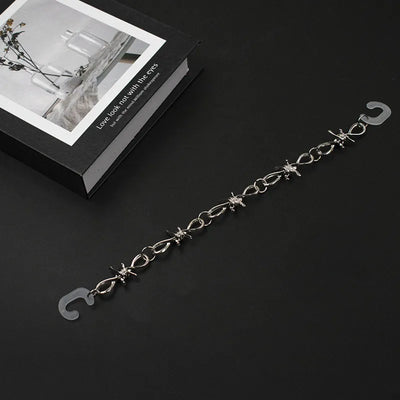 Silver chain for crocs on a black surface with a decorative box in the background