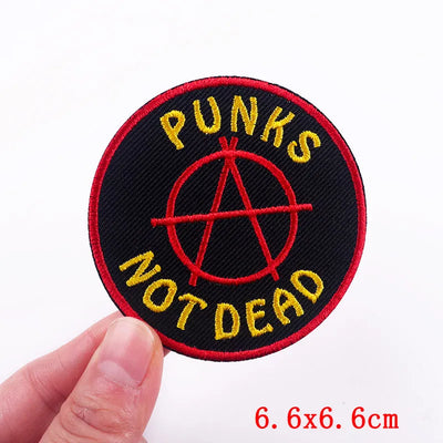 Patch with 'Punks Not Dead' text and anarchy symbol held by a hand on a white background.