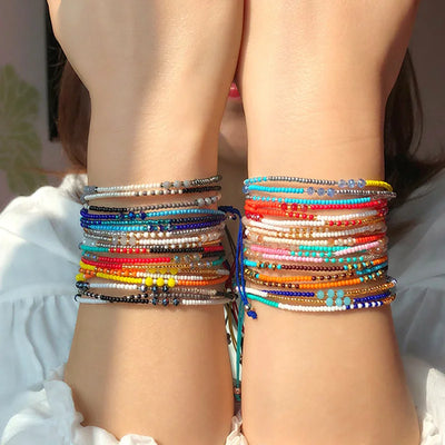 Multicolored beaded bracelets on a person's wrist with a blurred background