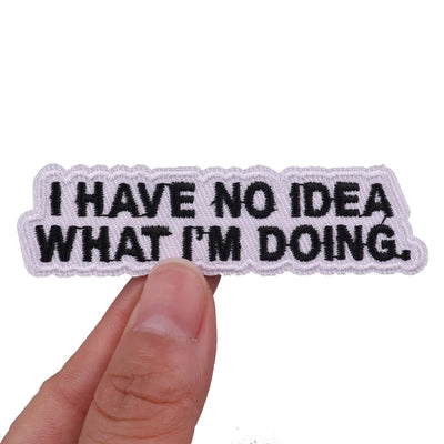 Patch with 'I HAVE NO IDEA WHAT I'M DOING.' text held by a hand on a white background