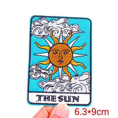 Embroidered patch of 'The Sun' tarot card held by a hand with size indication.