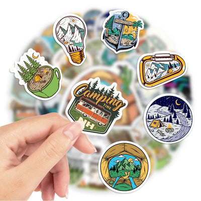 Collection of camping-themed stickers held by a hand with a blurred background
