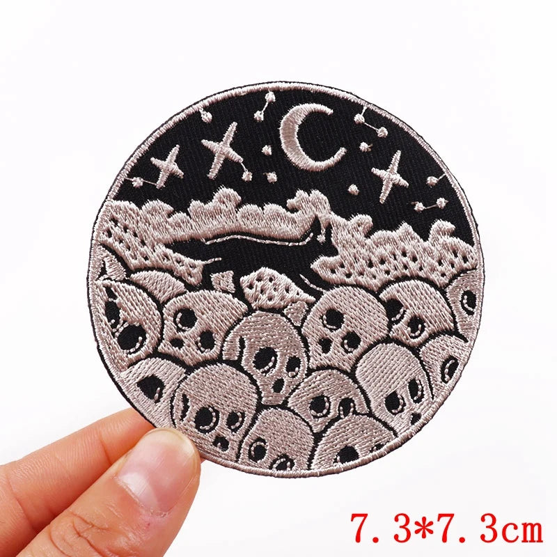 Circular patch with celestial design held by a hand, on a white background