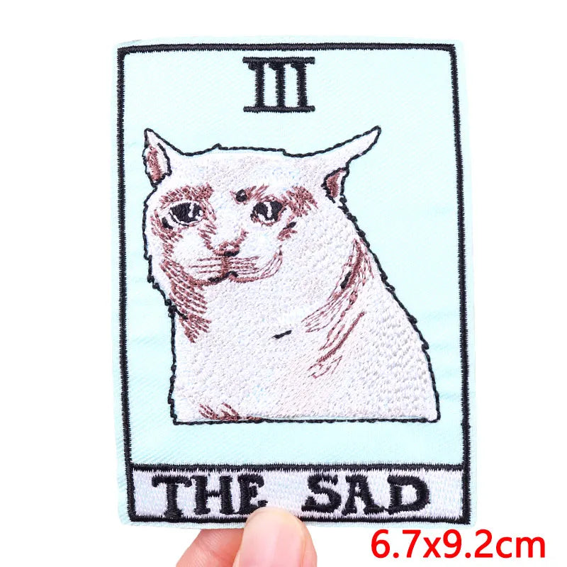 Embroidered patch of a cat with 'The Sad' text on a light blue background
