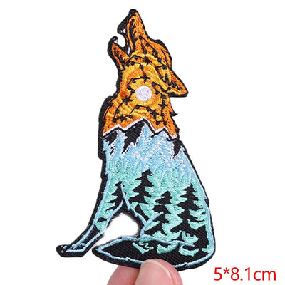Wolf patch with orange and blue design held by a hand on a white background