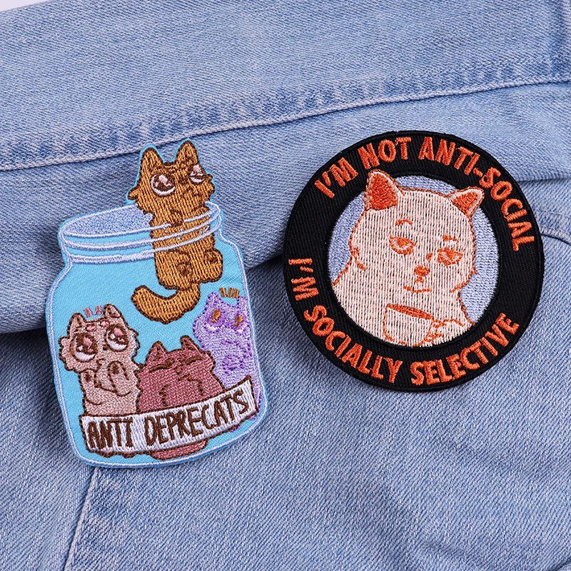Two cat-themed patches on a denim background