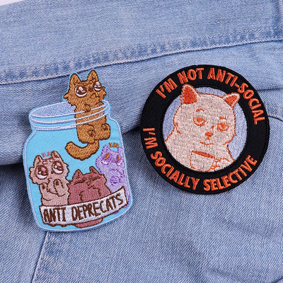 Two cat-themed patches on a denim background