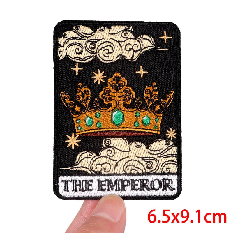 Embroidered patch with a crown design labeled 'The Emperor' held by a hand.