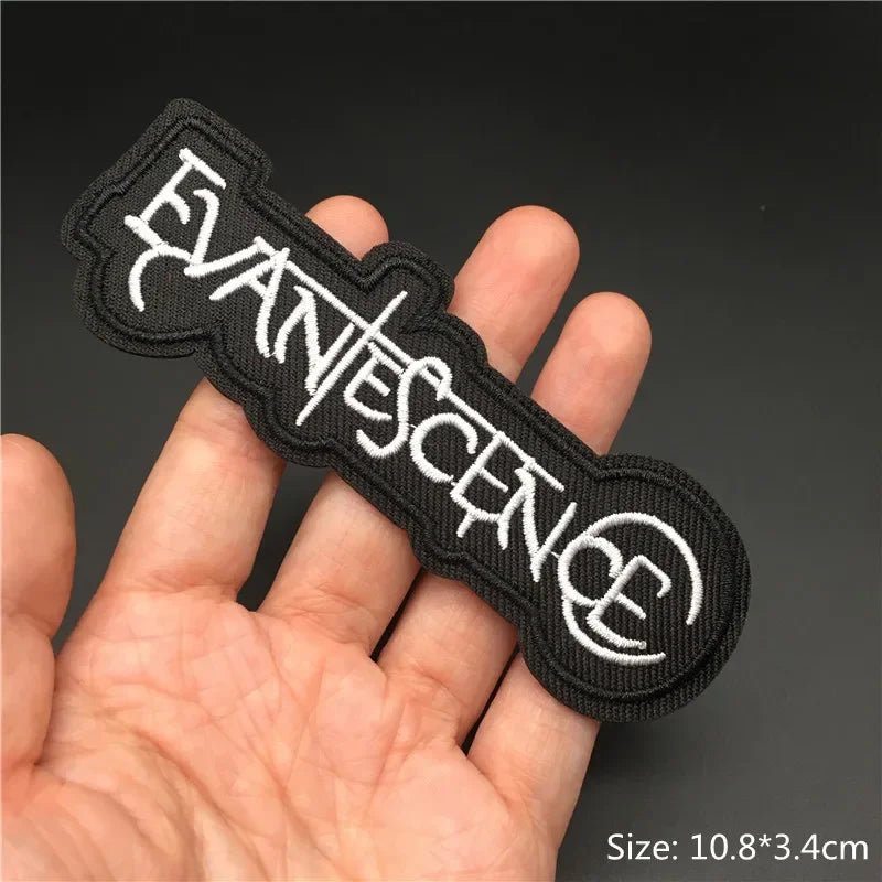 Hand holding a black and white Evanescence embroidered iron-on patch 10.8x3.4cm on a dark background