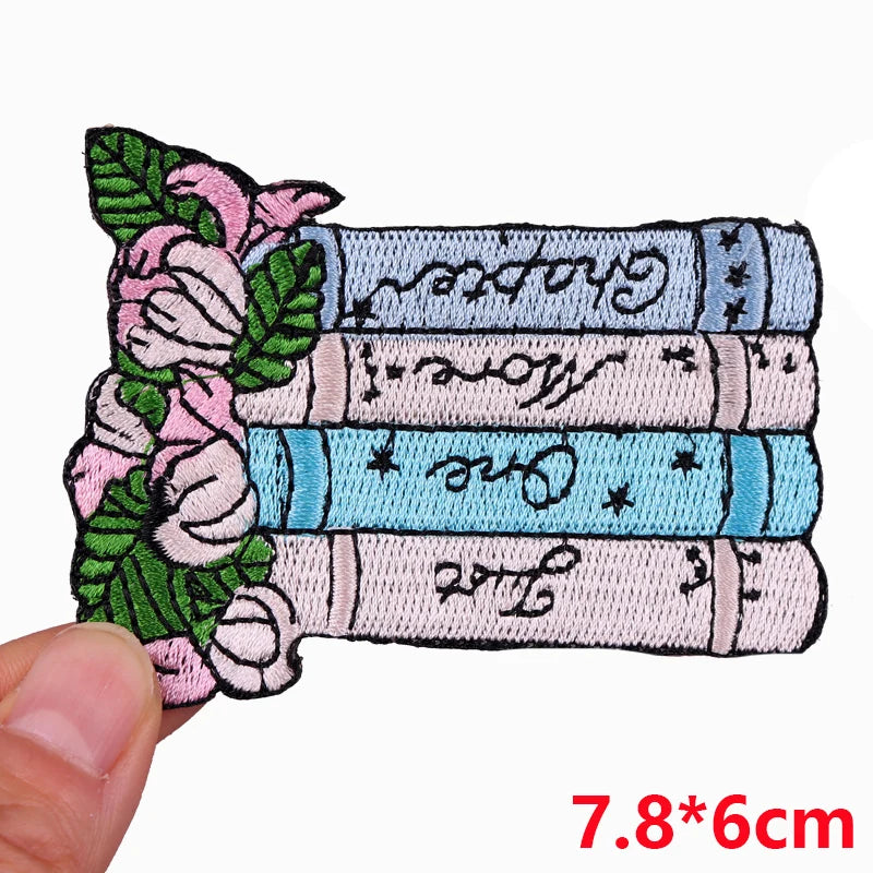 Embroidered patch with books and floral design held by a hand, size 7.8*6cm.