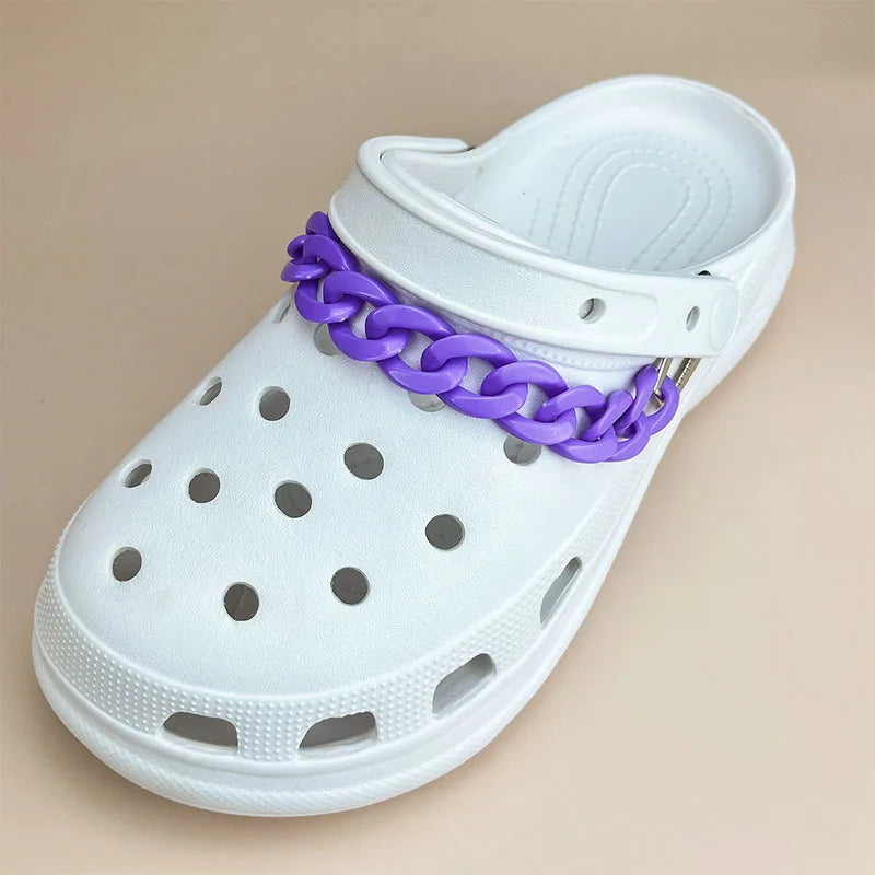 White clog shoe with a purple chain around the ankle area on a beige background
