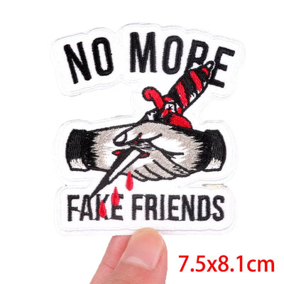 Sticker with 'No More Fake Friends' text and a hand holding a gun, held by a finger for scale.
