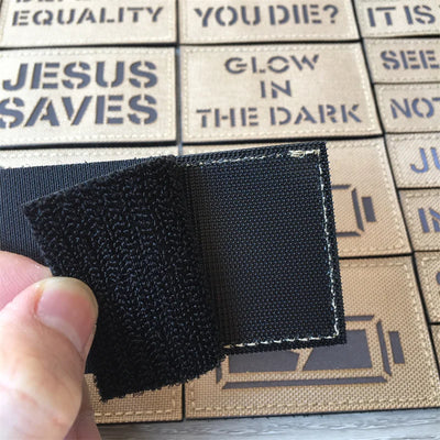 Black woven patch held over a background with text on tiles
