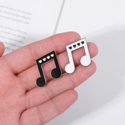 Music note-shaped enamel pin held in a hand with a blurred book background