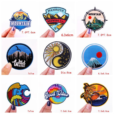 Collection of various embroidered patches with different designs and sizes, held by hands.