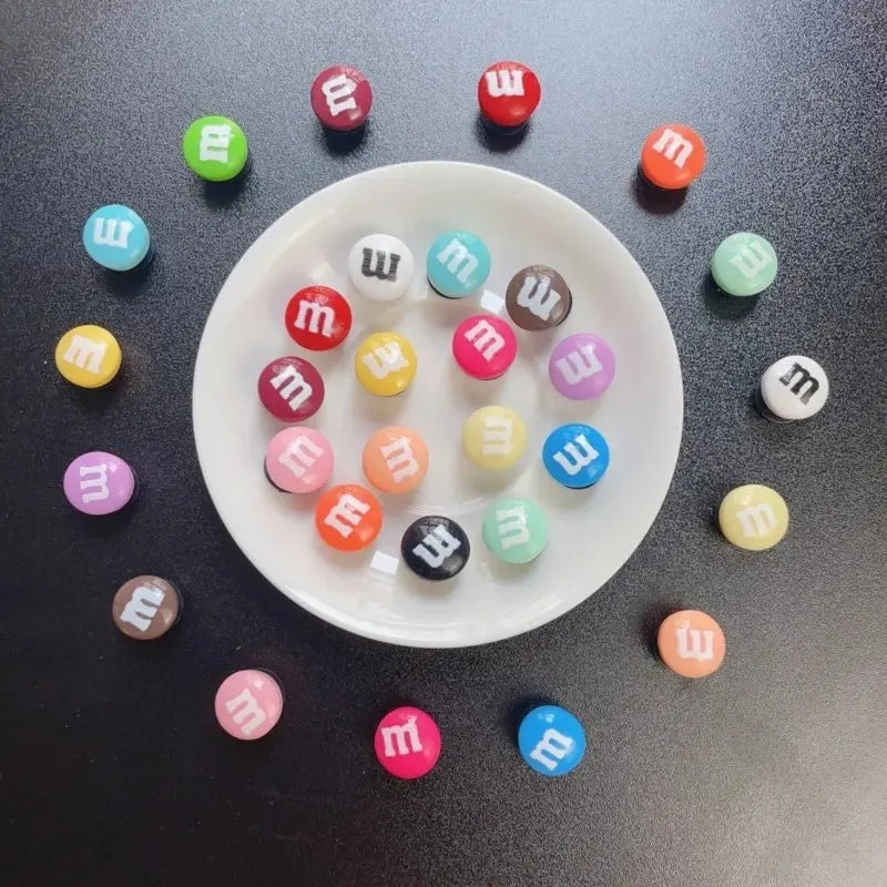 Colorful M&amp;M candies on a black surface with a white plate.
