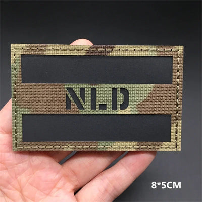 Netherlands flag camouflage patch held in a hand against a dark background