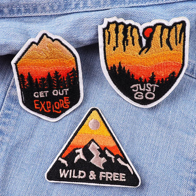 Three motivational patches with scenic designs and text on a denim background