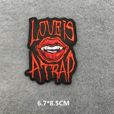 Embroidered patch with red lips and text 'LOVE IS ATTRACTION' on a gray background