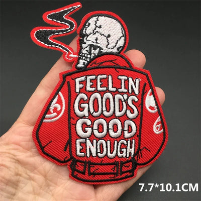 Embroidered patch with skull design and 'Feelin Good's Good Enough' text held in a hand.