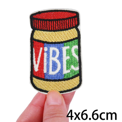 Colorful patch of a jar labeled 'VIBES' held by a hand on a white background